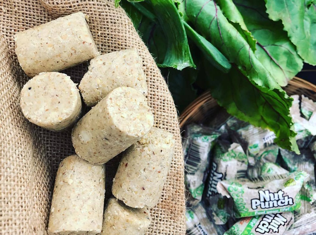 TerraNut Nut Punch cold-pressed snack bites on burlap fabric with wrapped bars and leafy greens in the background.